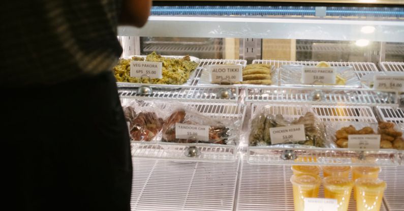 Payment Options - Back view of anonymous customer standing near glass showcase with assorted sweets while choosing delicious desserts in confectionery shop and making order