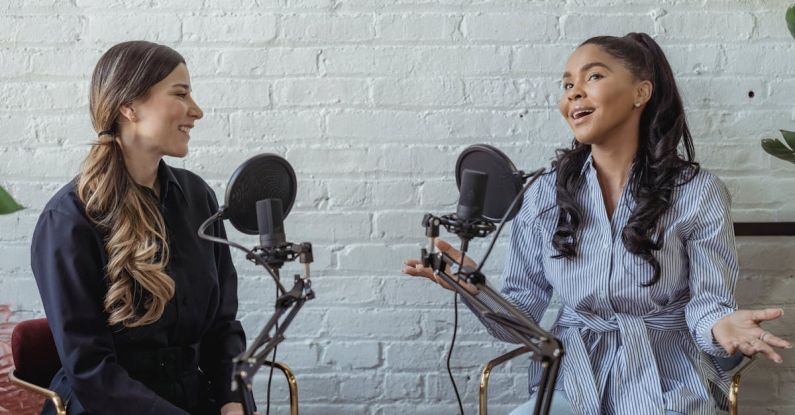 Podcast Formats - Smiling African American female guest gesticulating while having interview with journalist sitting near mic