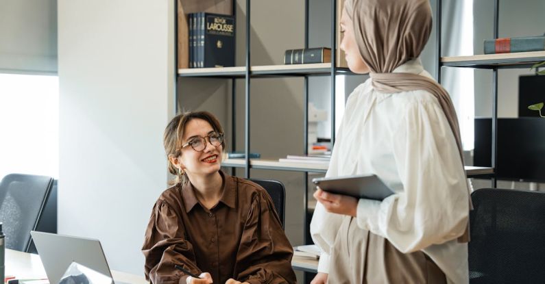 Aesthetic Planning - Two women in hijab talking in an office